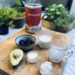 Ingredients for avocado blueberry smoothie on wooden chopping board and nutribullet in background