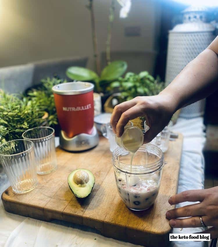 Pouring cream into blueberries before adding a halved avocado