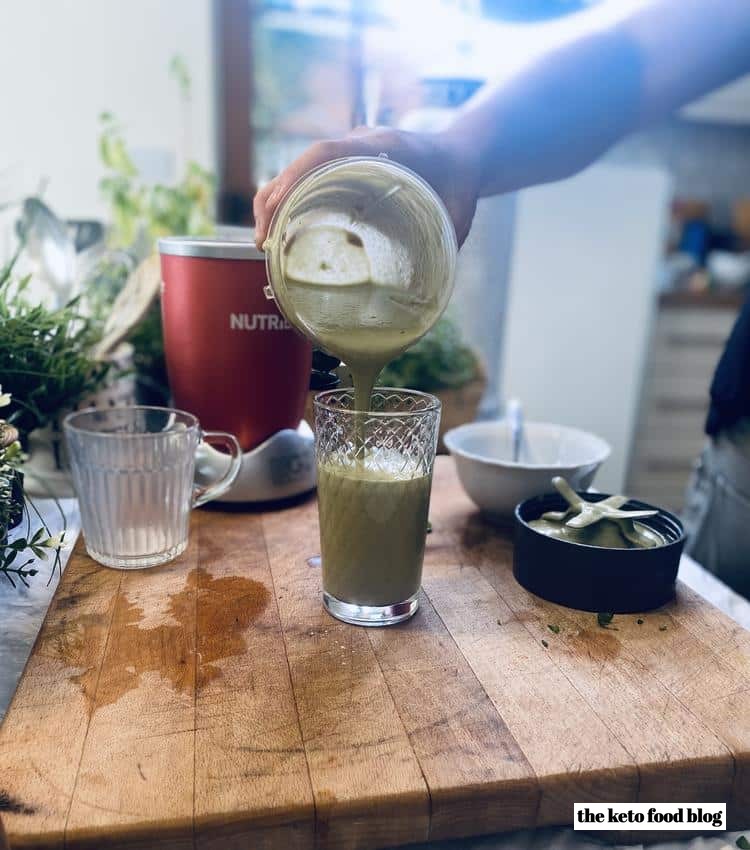 Pouring Ginger Basil Avocado Smoothie into cup from a Nutri-bullet