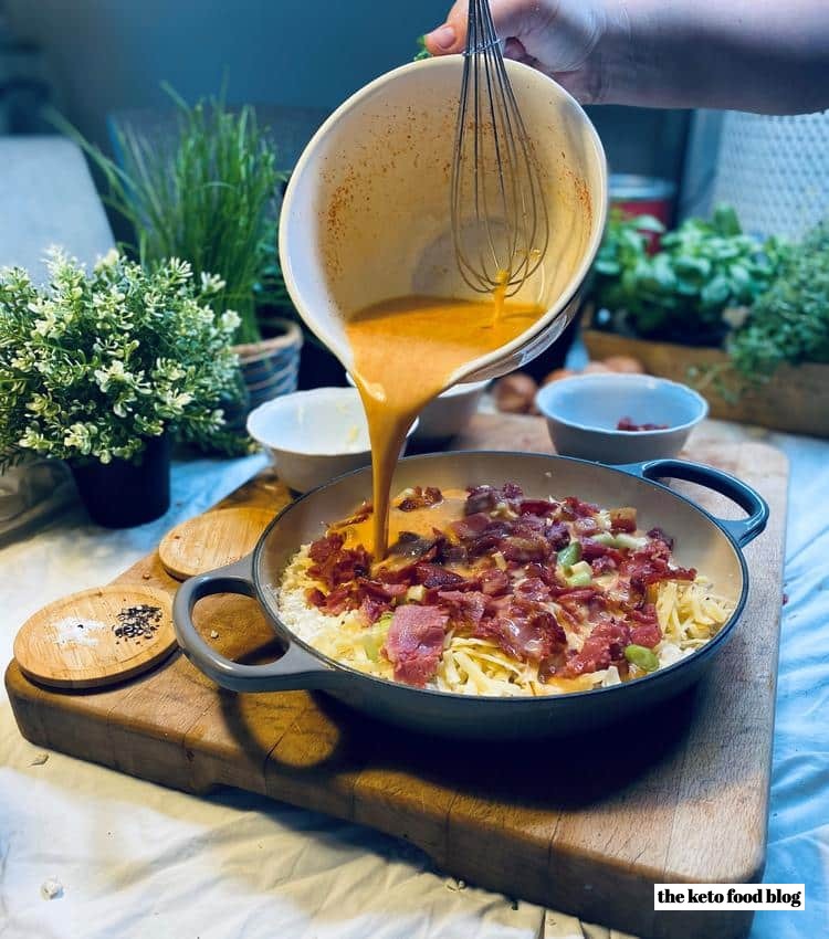 Pouring 9 whisked eggs into baking dish for cauliflower omelet