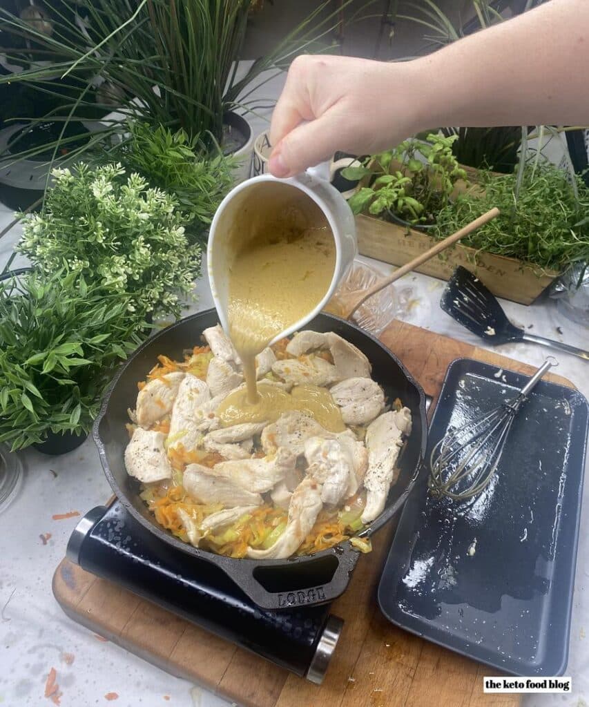 Pouring a mustard sauce over chicken and vegetables