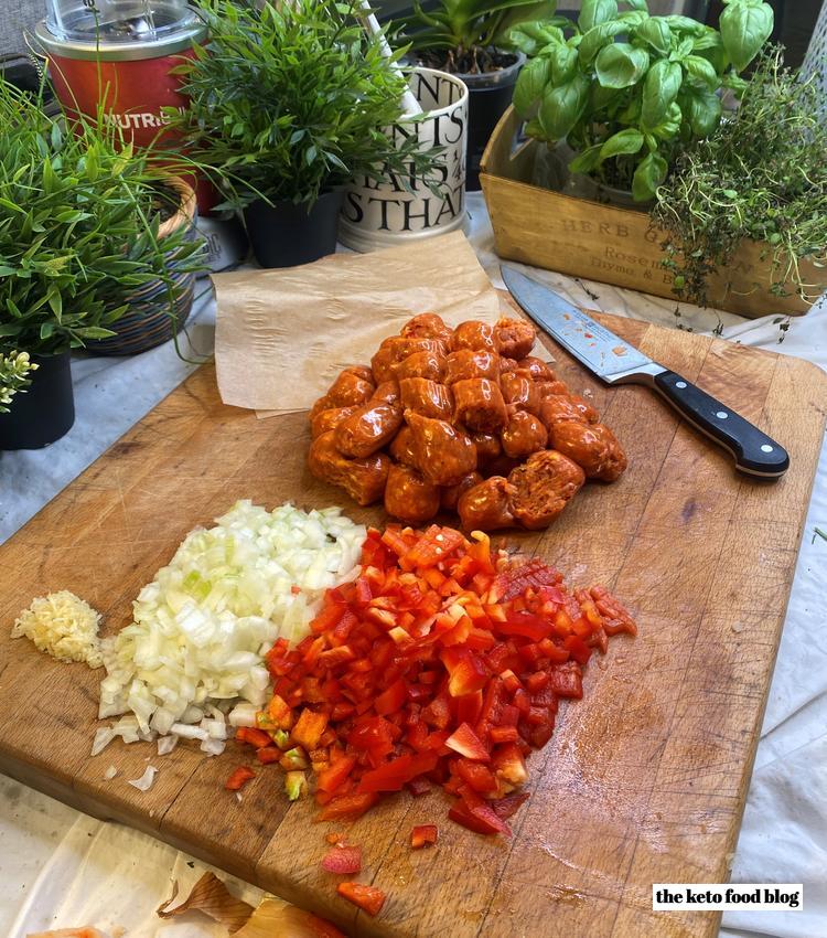Chopped white onion, red pepper and italian sausage on a chopping board