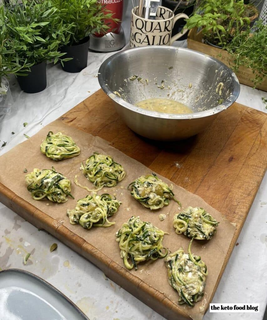 Greek Zucchini and Feta Fritters on a chopping board with a mixing bowl in the background