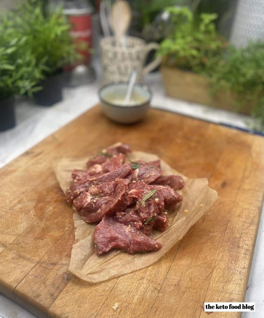 Steak rubbed with ghee and seasoning on baking parchment ready to be cooked