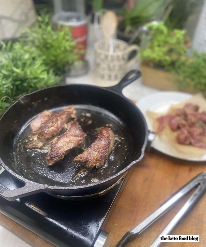 Steak strips cooking on a skillet