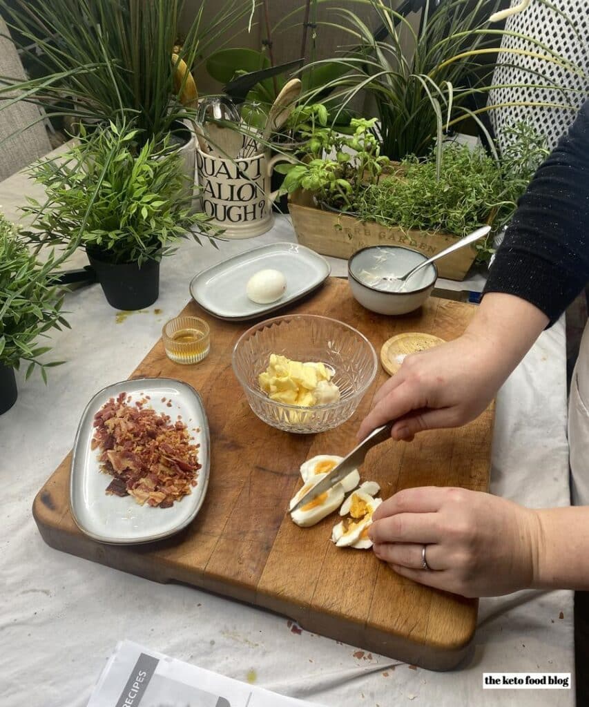 Slicing a hard boiled egg on a wooden chopping surrounded by other ingredients