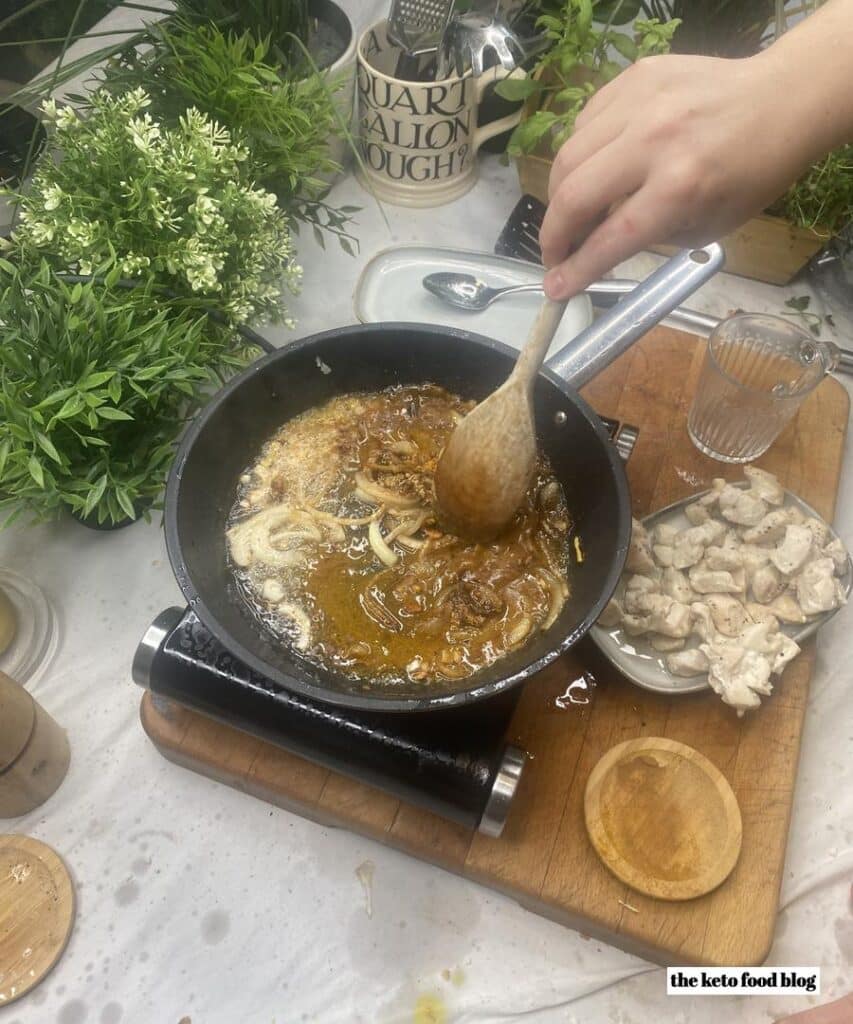 Mixing indian spices into onions in a pan with a wooden spoon