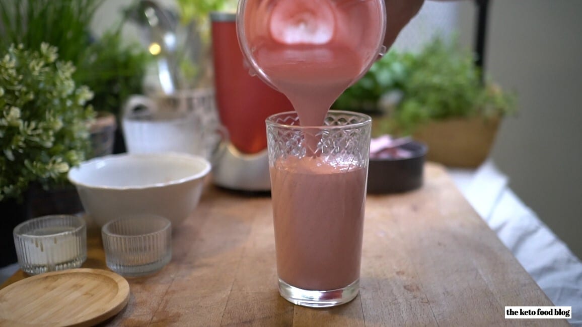 Pouring a strawberry sage smoothie into a glass from a nutribullet