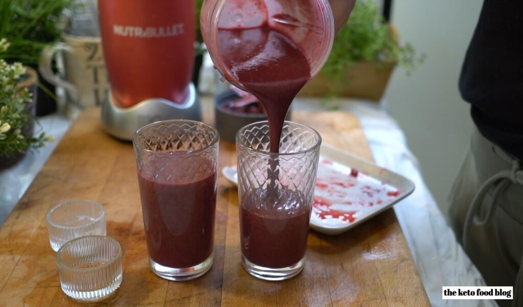 Pouring three berries smoothie into a glass from a nutribullet