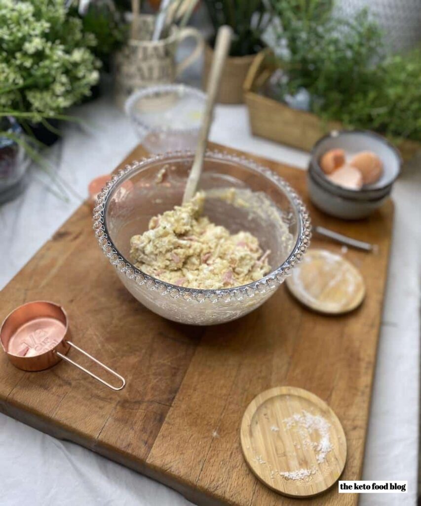 Mixing ingredients for keto scones in a glass french bowl on a wooden chopping board