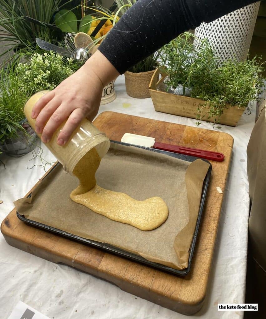 Pouring out Keto-dough on to a baking sheet lined with parchment paper